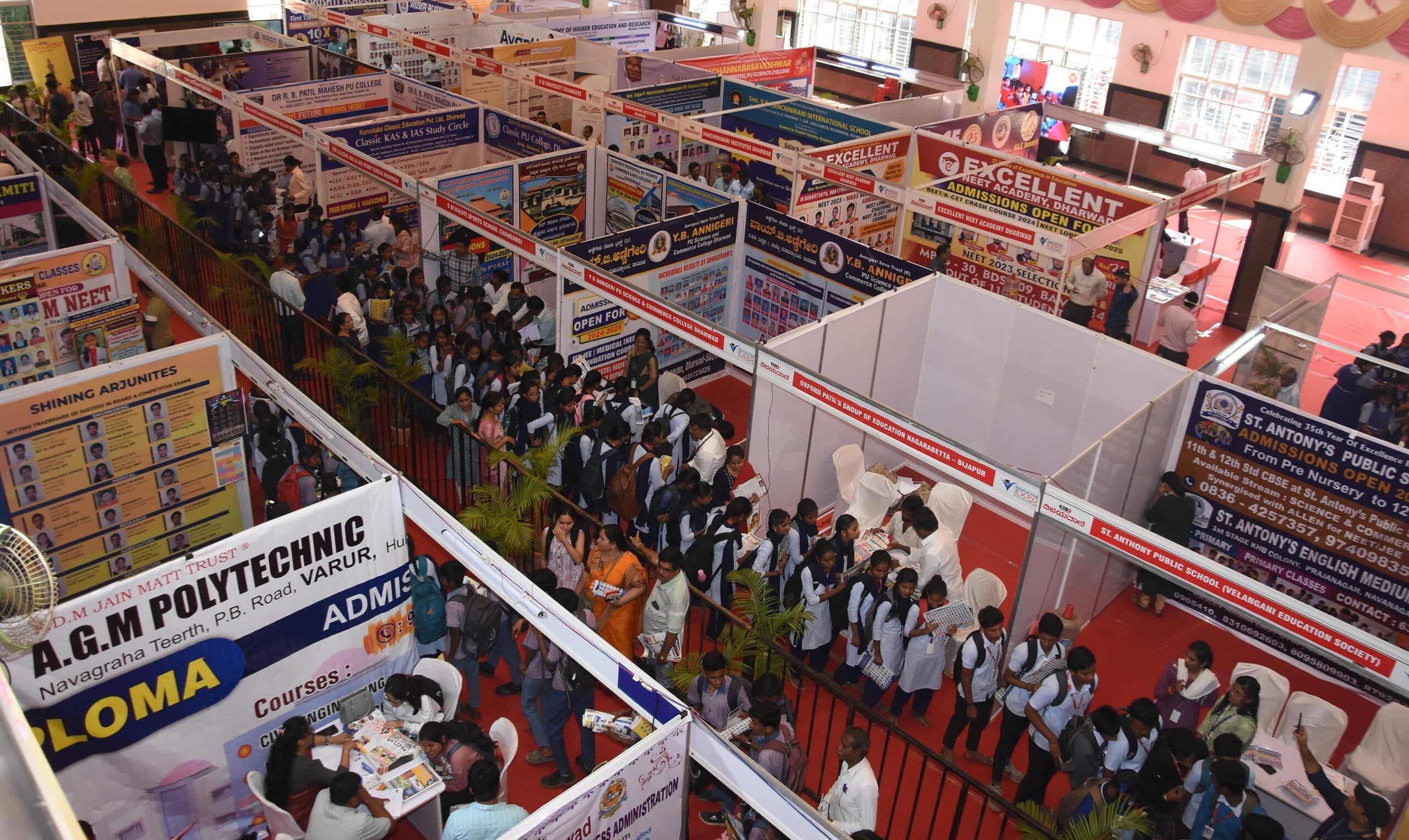 A crowded expo hall aisle lined with branded education stands