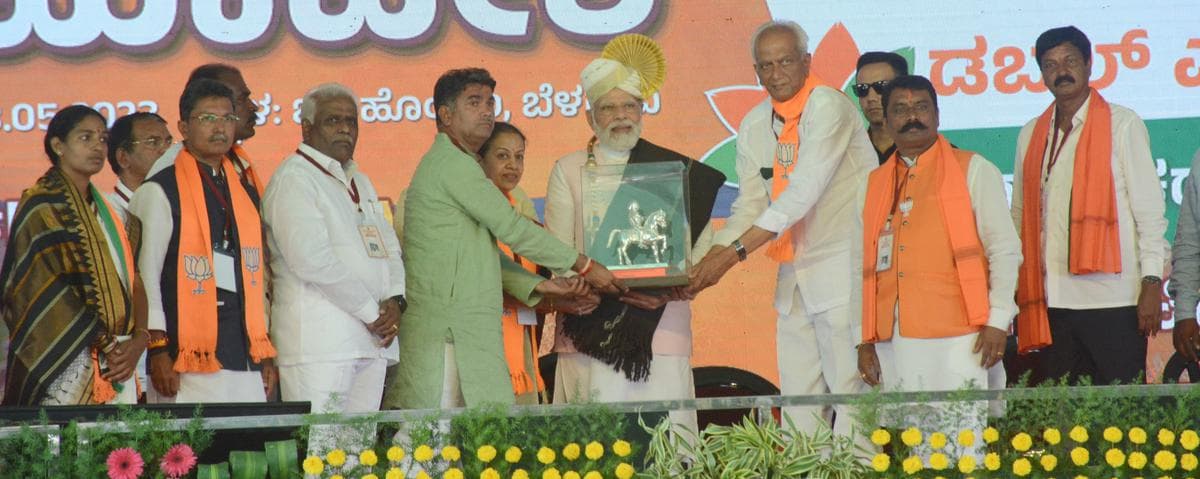 Guests exchanging a memento on stage amid marigold arrangements