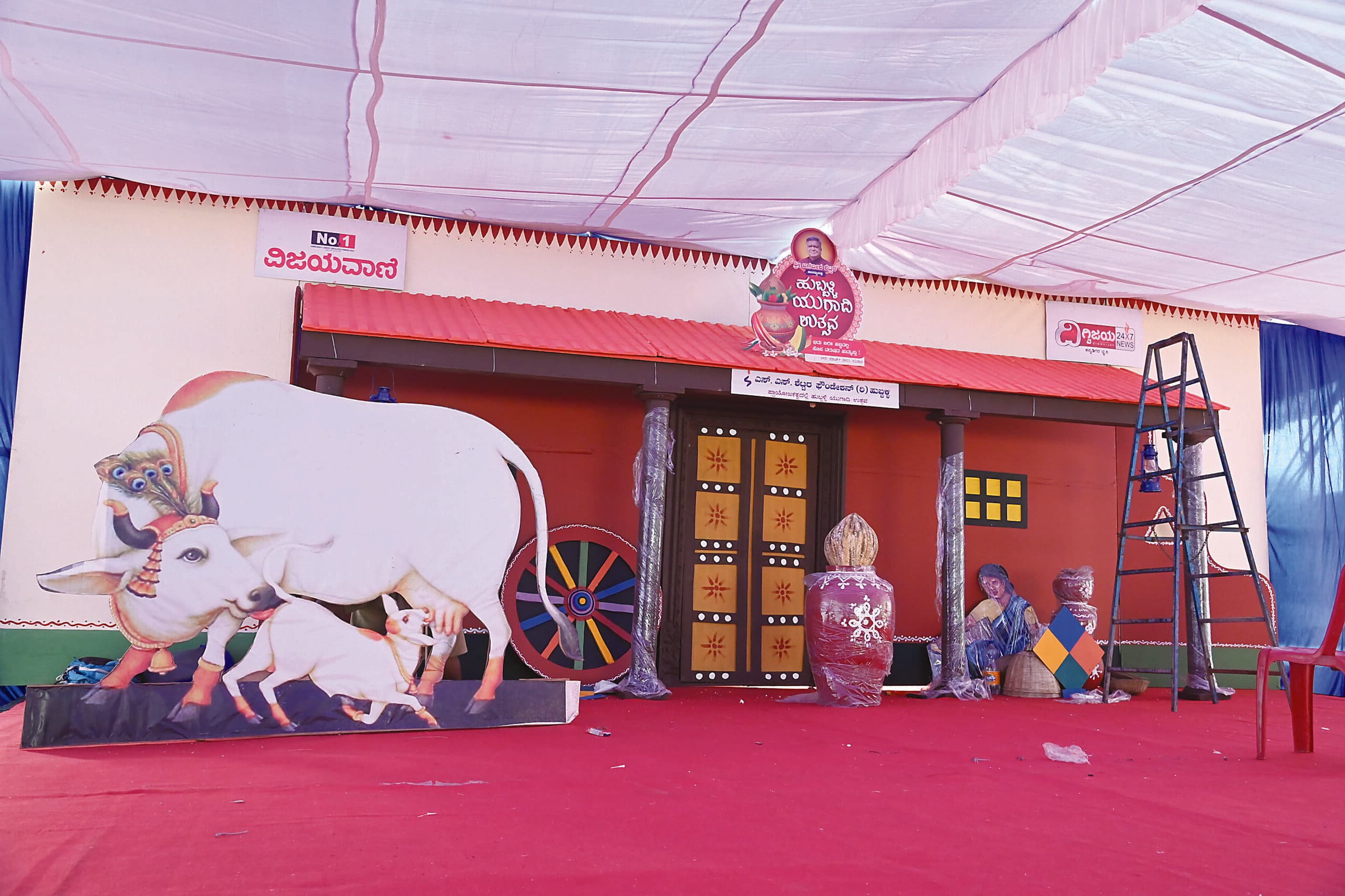 Green-lit festival stage dressed with a sculpted bull and rangoli