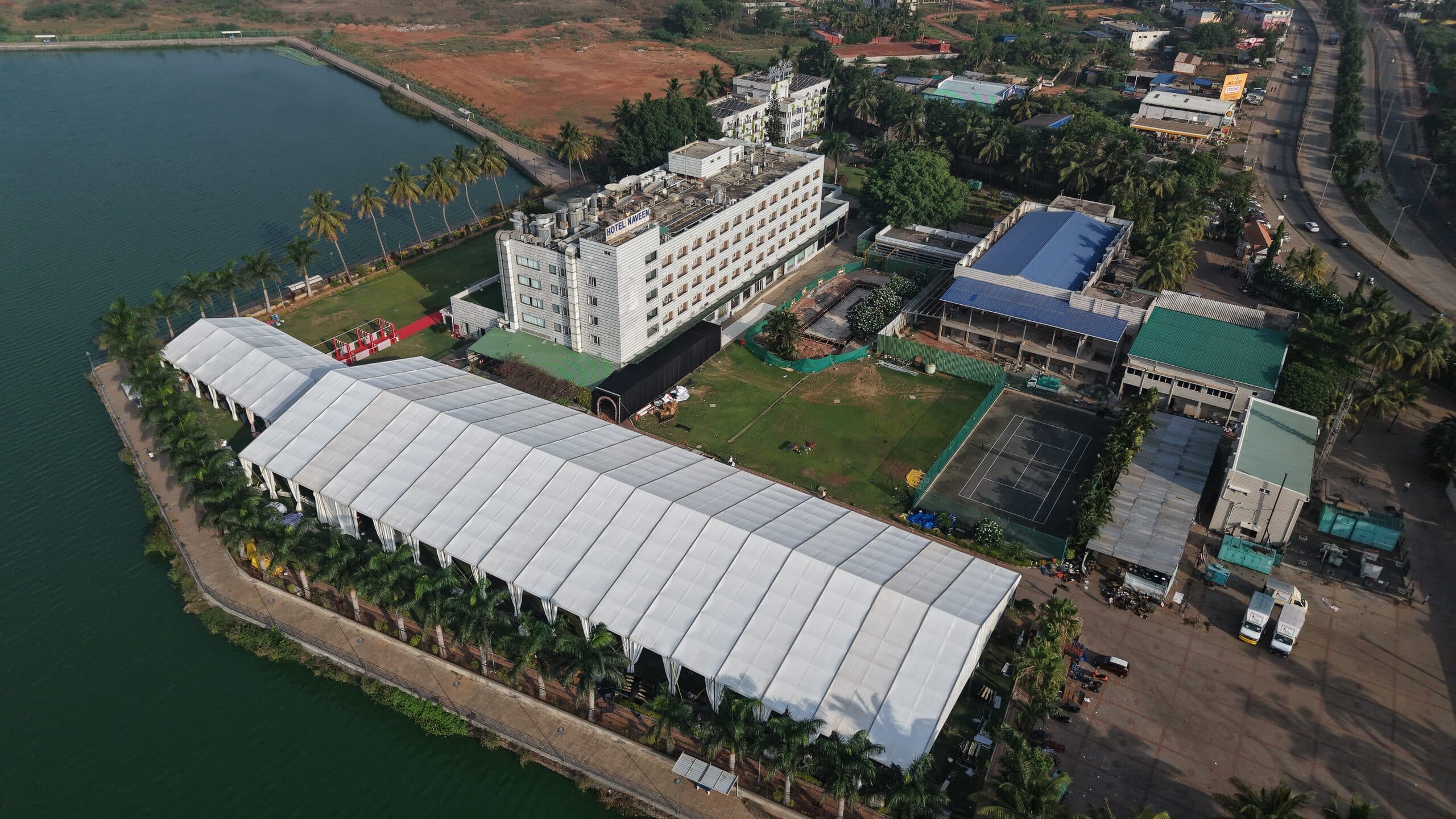 An aerial view of long white event marquees built along a lakeside campus