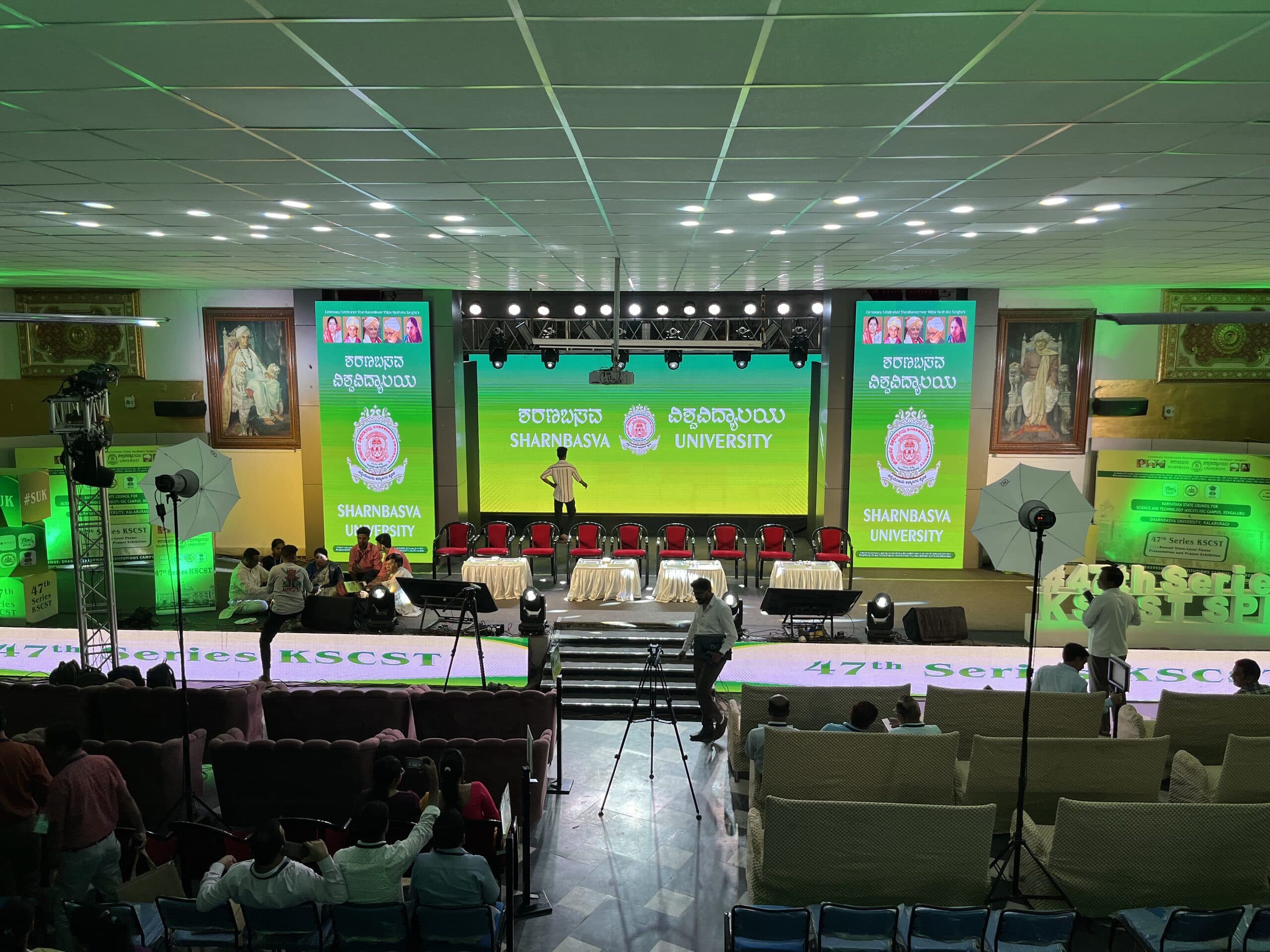 The presentation stage between two umbrella lights, front rows already filled