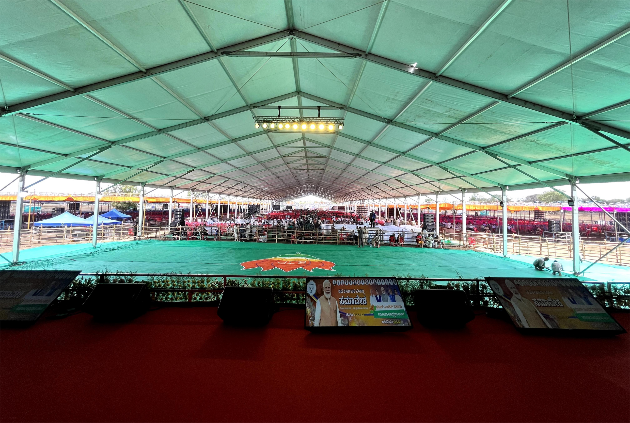 Vast marquee interior laid with green carpet in front of the ceremonial stage