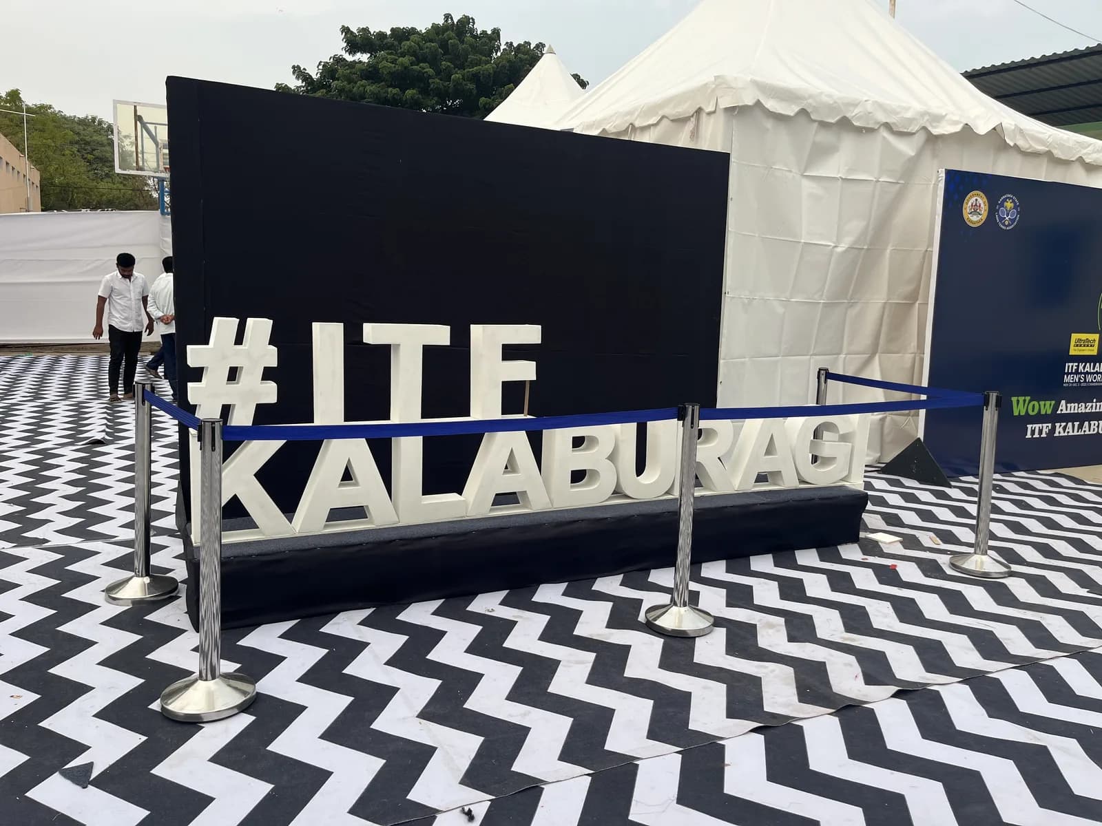 Three-dimensional #ITF Kalaburagi letters on a black and white chevron carpet