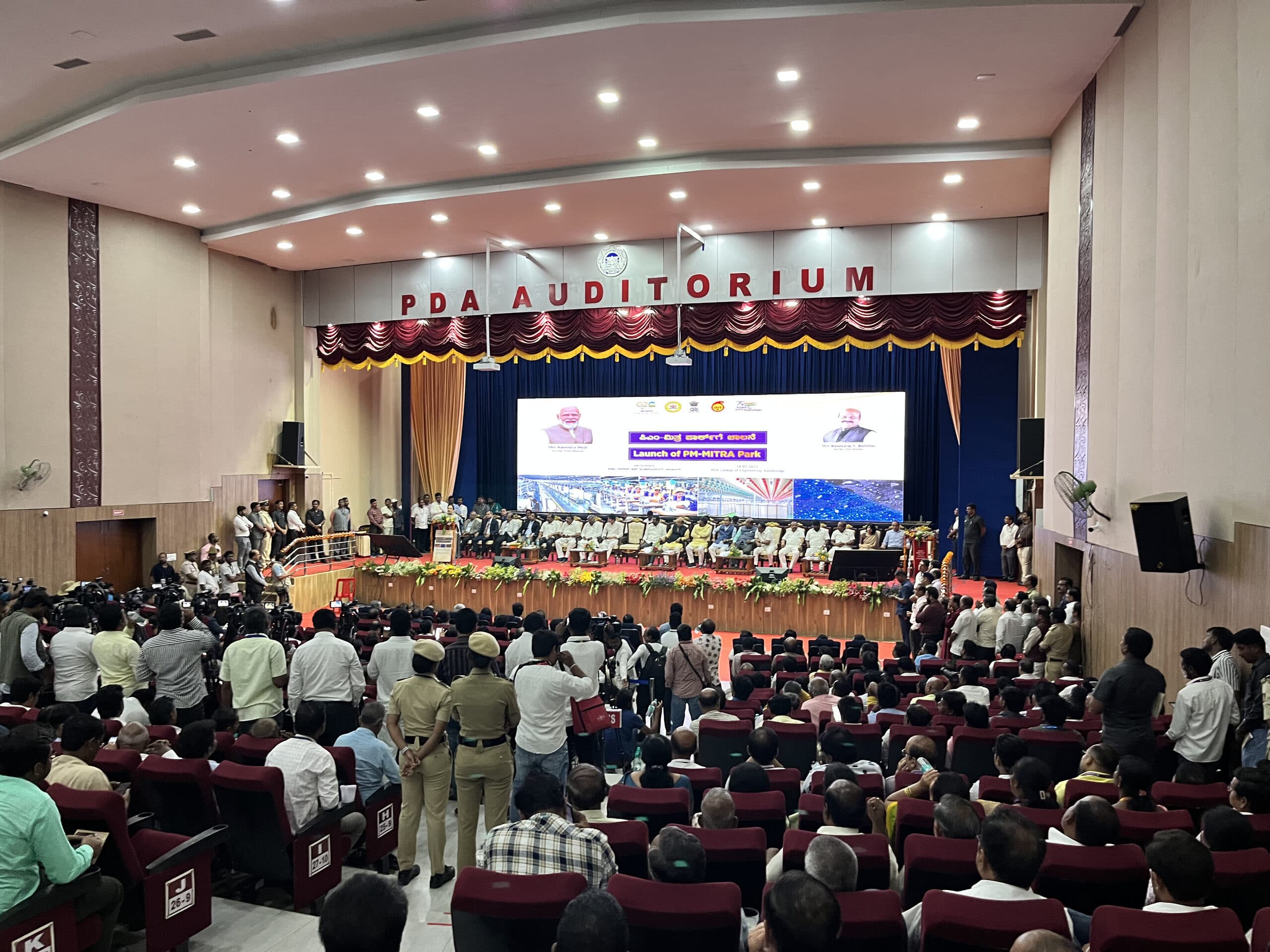 Full PDA Auditorium at the launch ceremony, the stage screen carrying the announcement